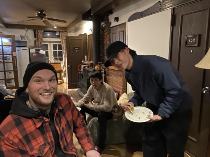 ニセコの室内で若年成人の男性3人、皿を持つ